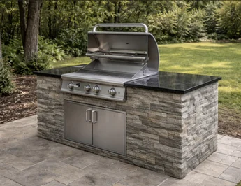 Finished grill island with stone finish and dark countertop on a patio